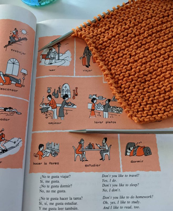 Image of a 1980's era Spanish textbook and a knit washcloth