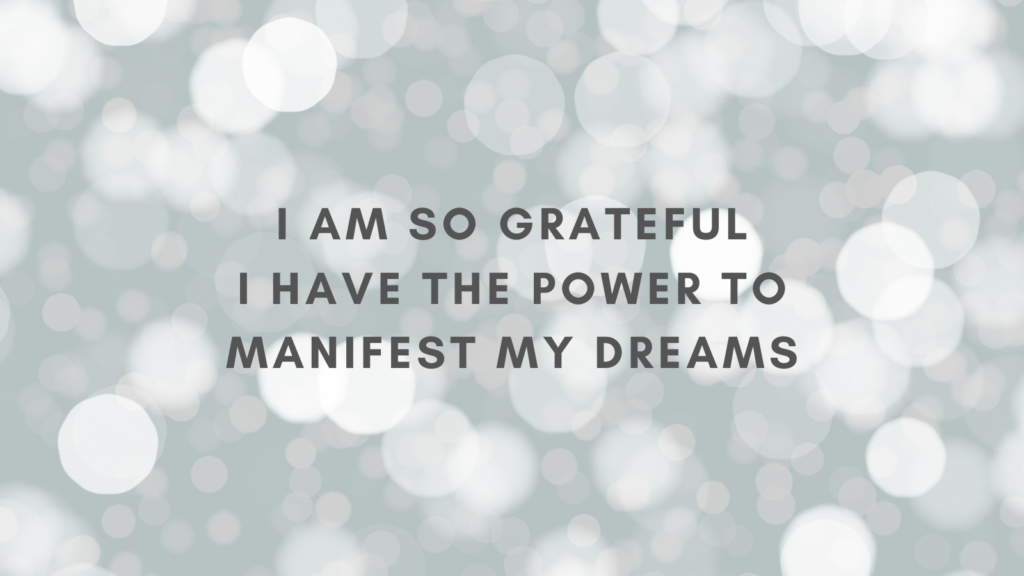 Image of out of focus lights, with the words, "I am so grateful I have the power to manifest my dreams" written over the image.